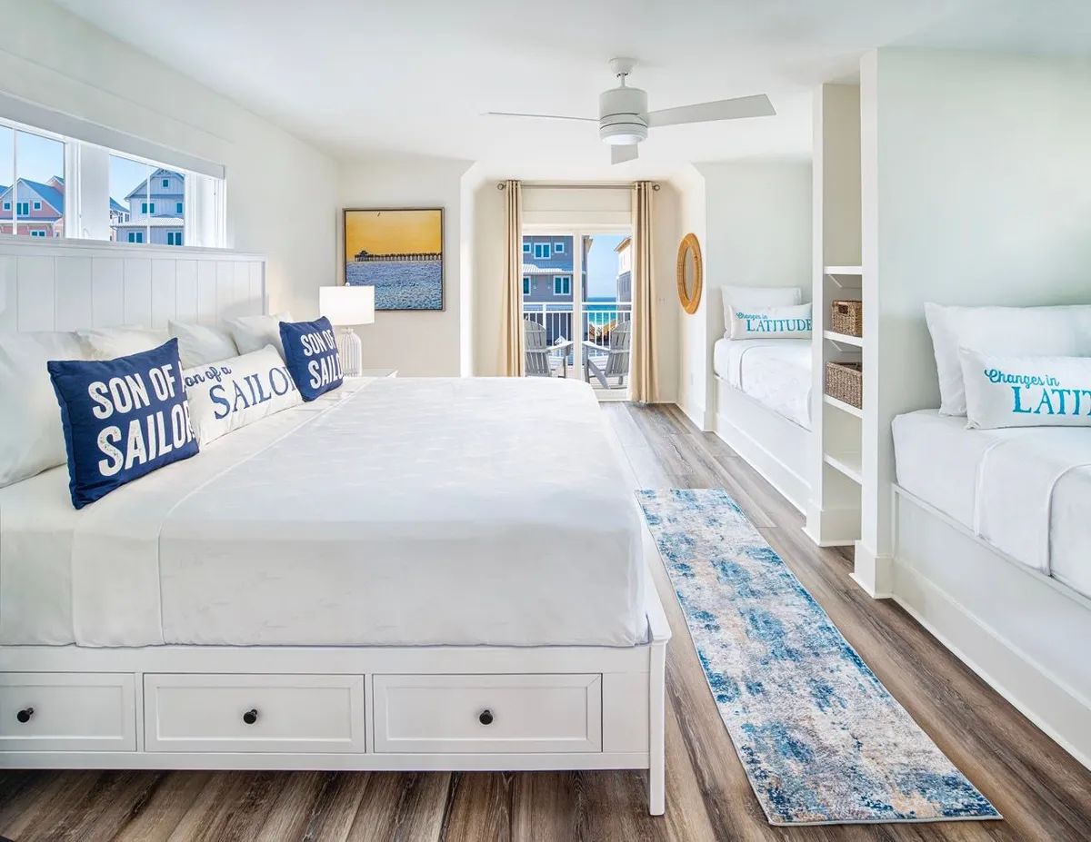 A cheerful and functional bedroom that combines a large bed with decorative pillows and a set of cozy bunk beds. The space is enhanced by playful wall art, making it perfect for families or groups. The overall mood is both tranquil and lively, ideal for relaxation as well as shared moments like storytelling or game nights.